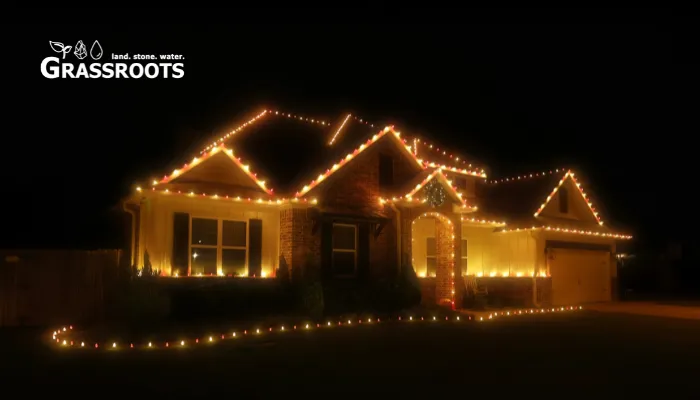 Brick home outlined with warm white Christmas lights installed by Grassroots at night.