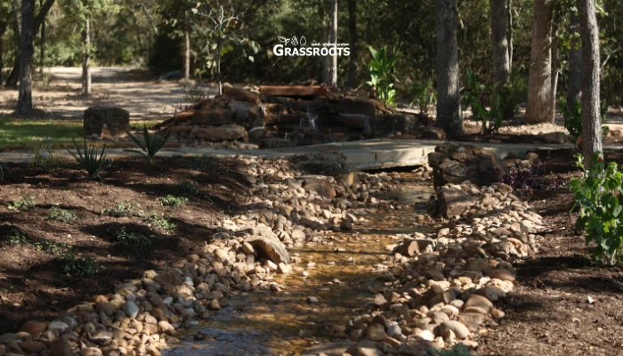 Creek in a backyard with running water, showing Drainage Solutions That Protect Your Yard and Home - Grassroots managing stormwater flow.